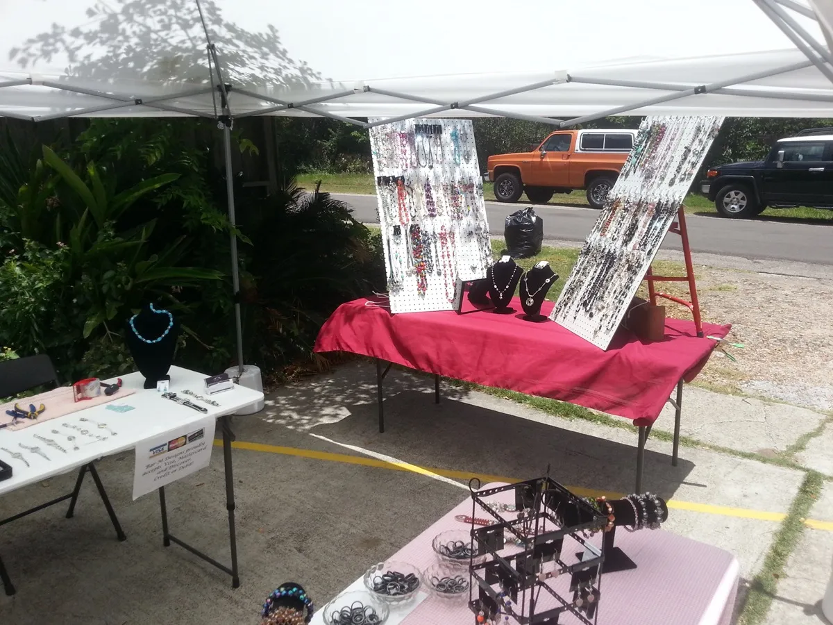 Seller at craft show booth with full jewelry display