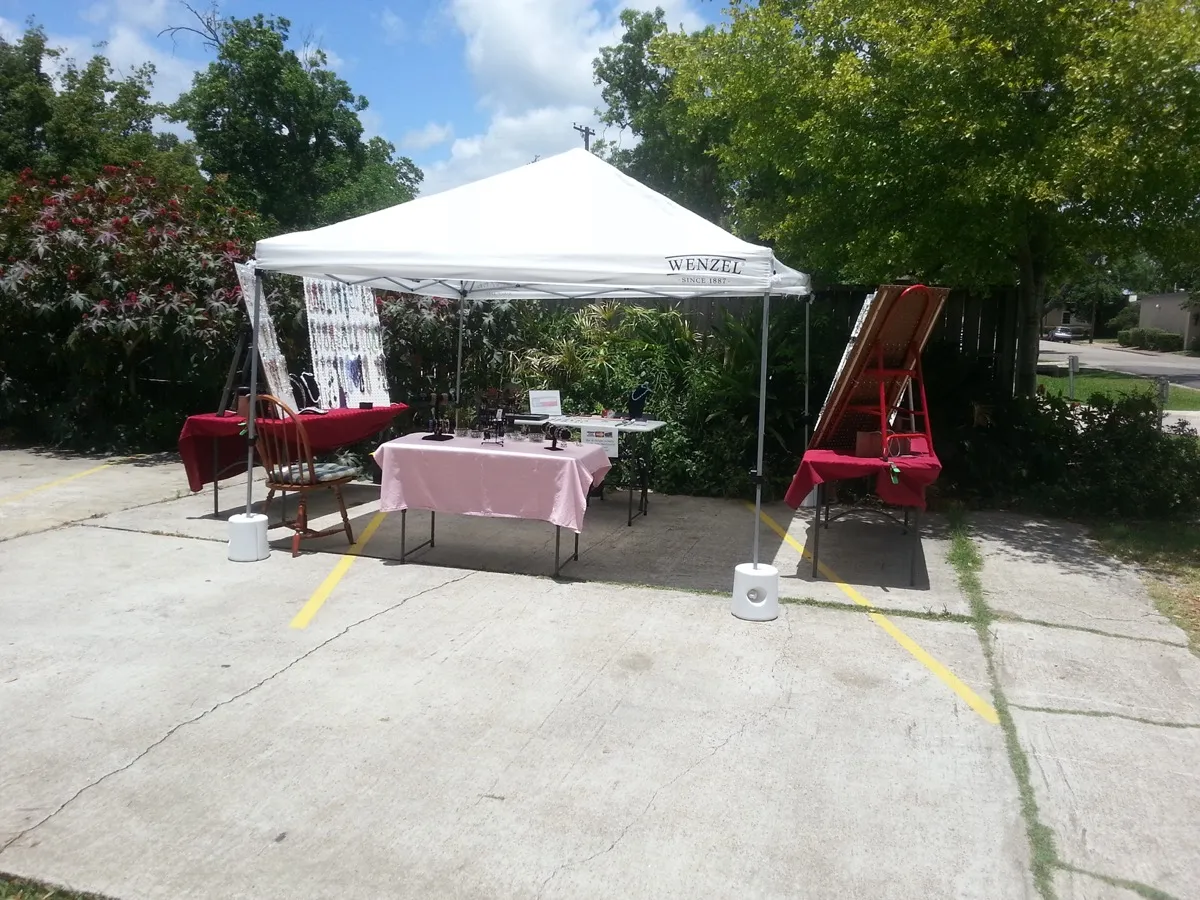 Outdoor craft show booth with popup tent and table setup